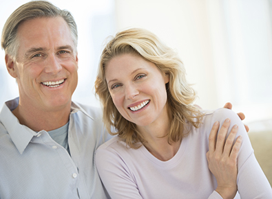 Mature smiling white couple sitting on couch
