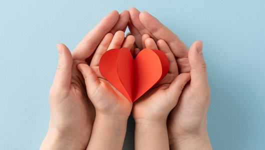 two people holding a paper heart