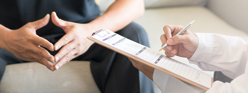 Doctor writing on clipboard with patient