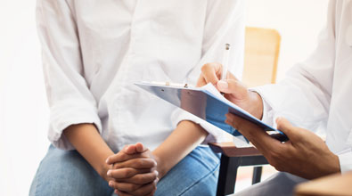 Women waiting on physician to finalize writing on a clipboard.