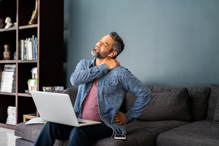 Man at desk rubbing back