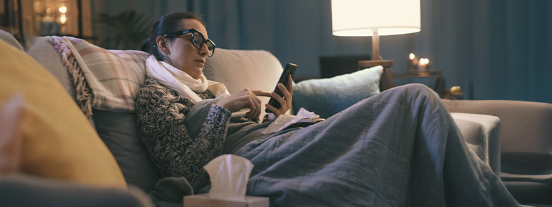 sick woman looking at her phone